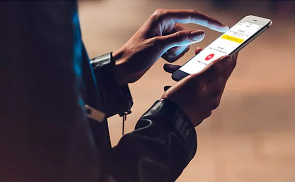 Servicio ContiGo Primer plano de unas manos sosteniendo un móvil con la app de Movistar Prosegur Alarmas abierta y su Botón SOS