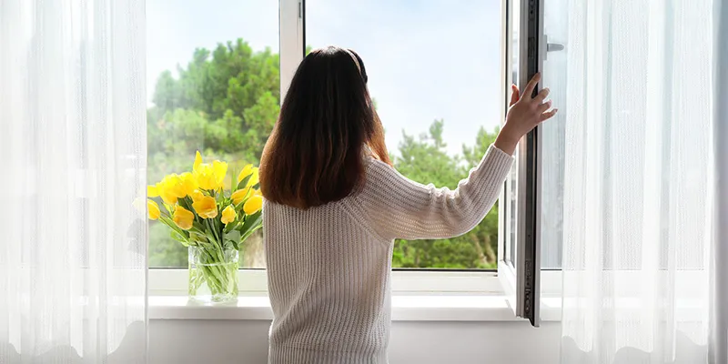 Mujer abriendo una ventana por fuga de gas en casa