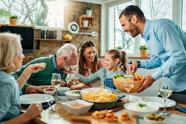 Seguridad en el hogar Familia alrededor de una mesa llena de alimentos comiendo felices